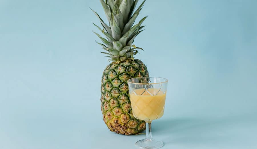 fruity shake in a glass next to a whole pineapple